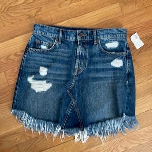 Distressed denim mini skirt with frayed edge.